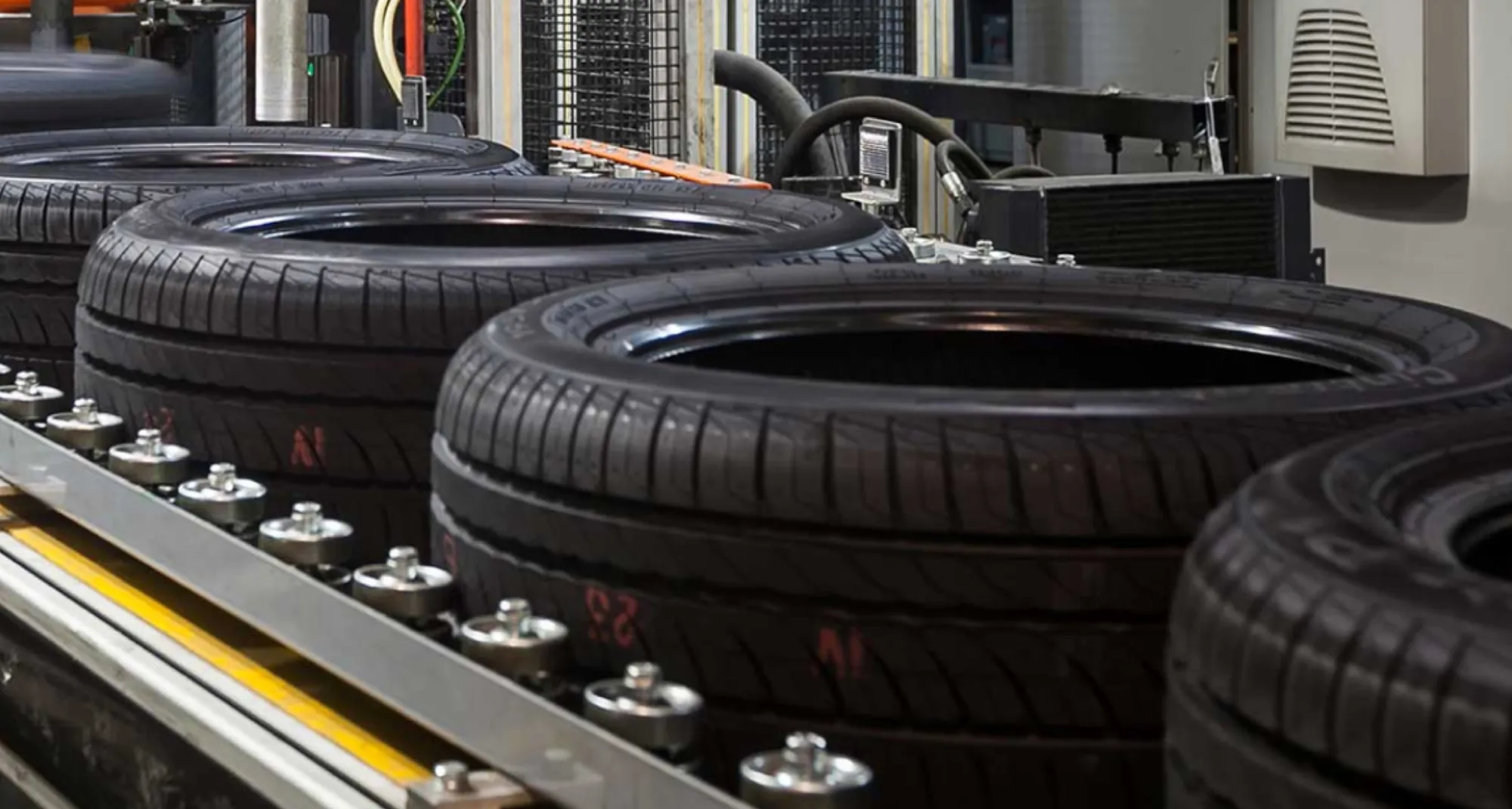 Row of car tyres on a conveyor in the factory