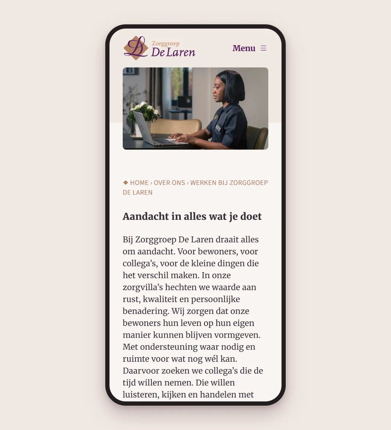 Smartphone showing the Working at Zorggroep De Laren page: a staff member in uniform at a laptop and the heading ‘Aandacht in alles wat je doet’ (attention in everything you do)